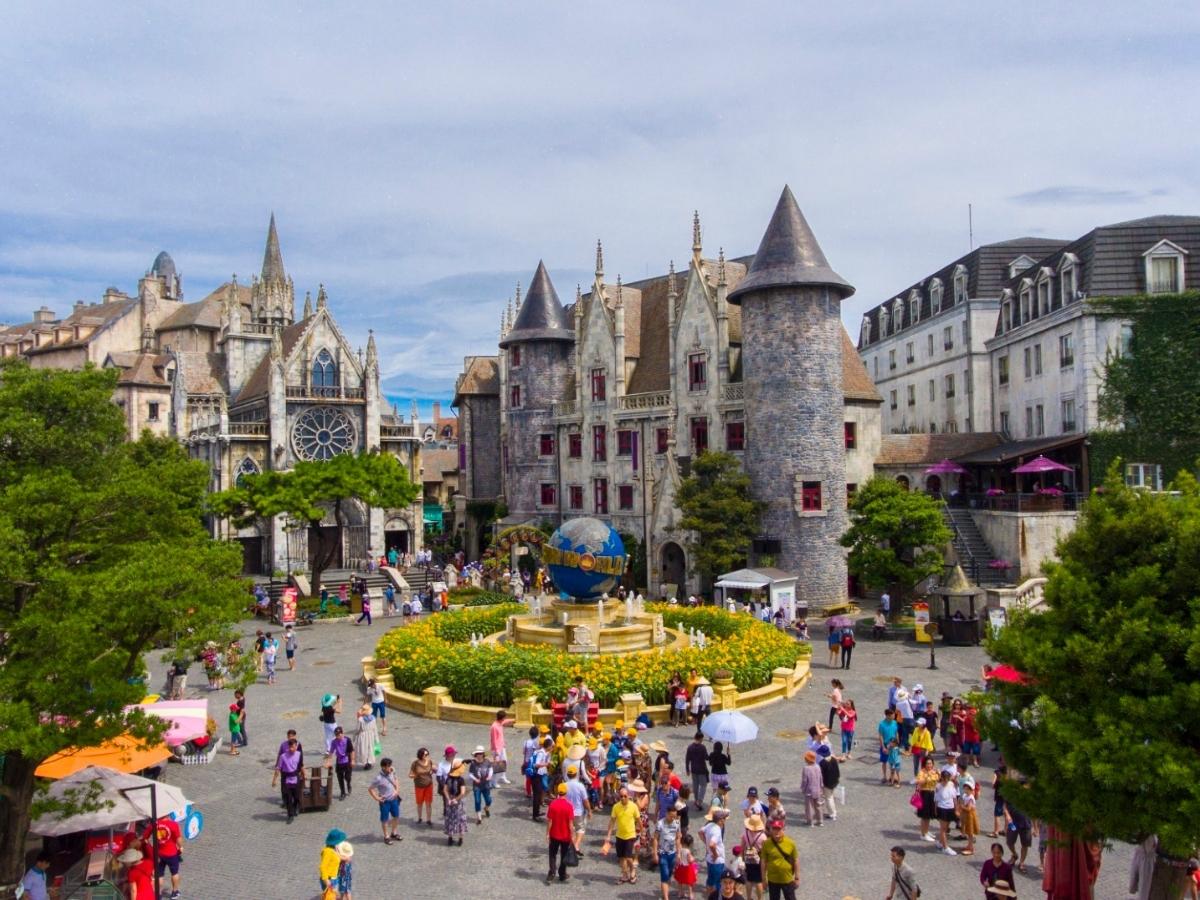 A French-style village square with a clock tower and pastel buildings at Ba Na Hills