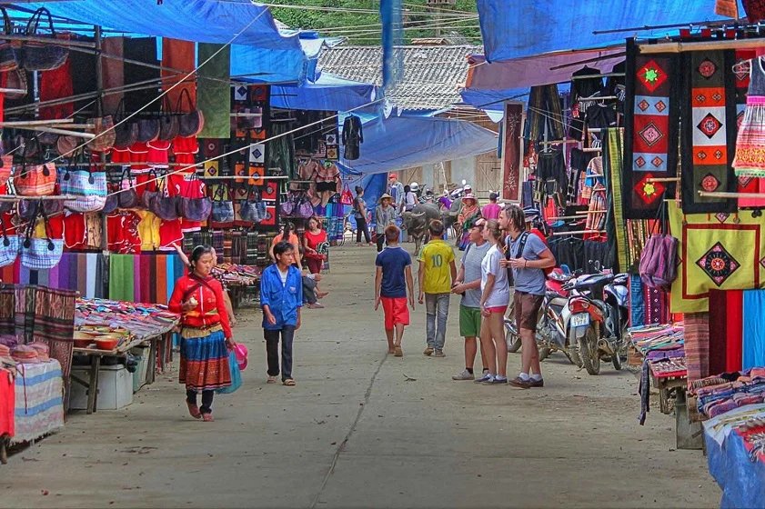 A busy highland market with colourful embroidered clothing and fabrics for sale