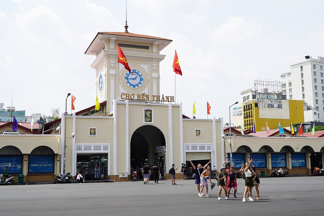The clock tower over the main gate of Ben Thanh Market in Ho Chi Minh City, with visitors outside