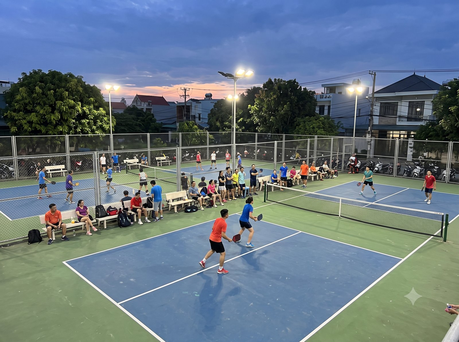 A busy pickleball court in Vietnam with several games and players waiting