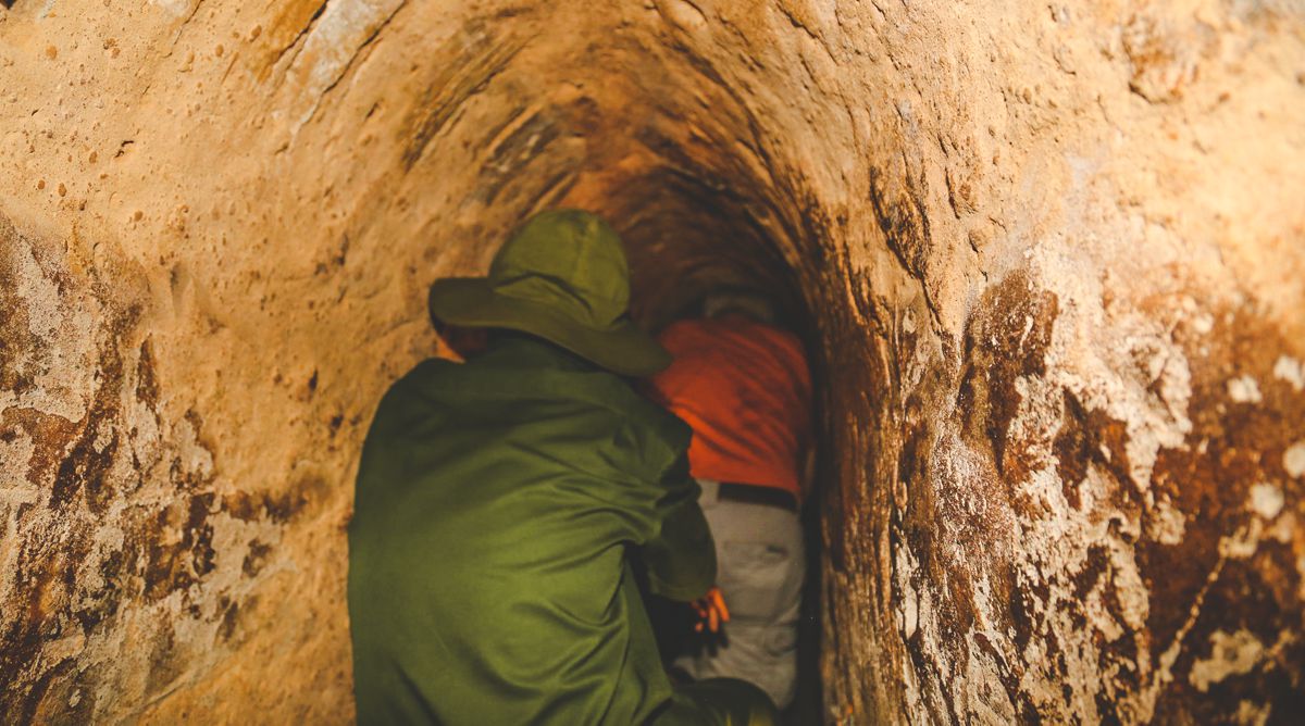 A visitor crawling through a widened section of the Cu Chi Tunnels