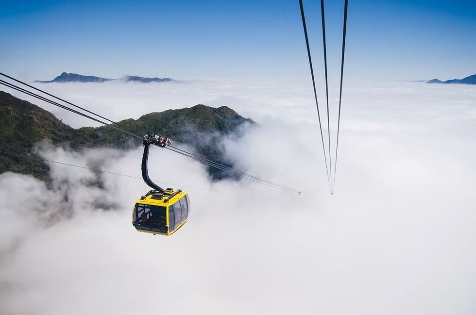 A cable car gondola rising above a sea of clouds towards Fansipan mountain in Sapa