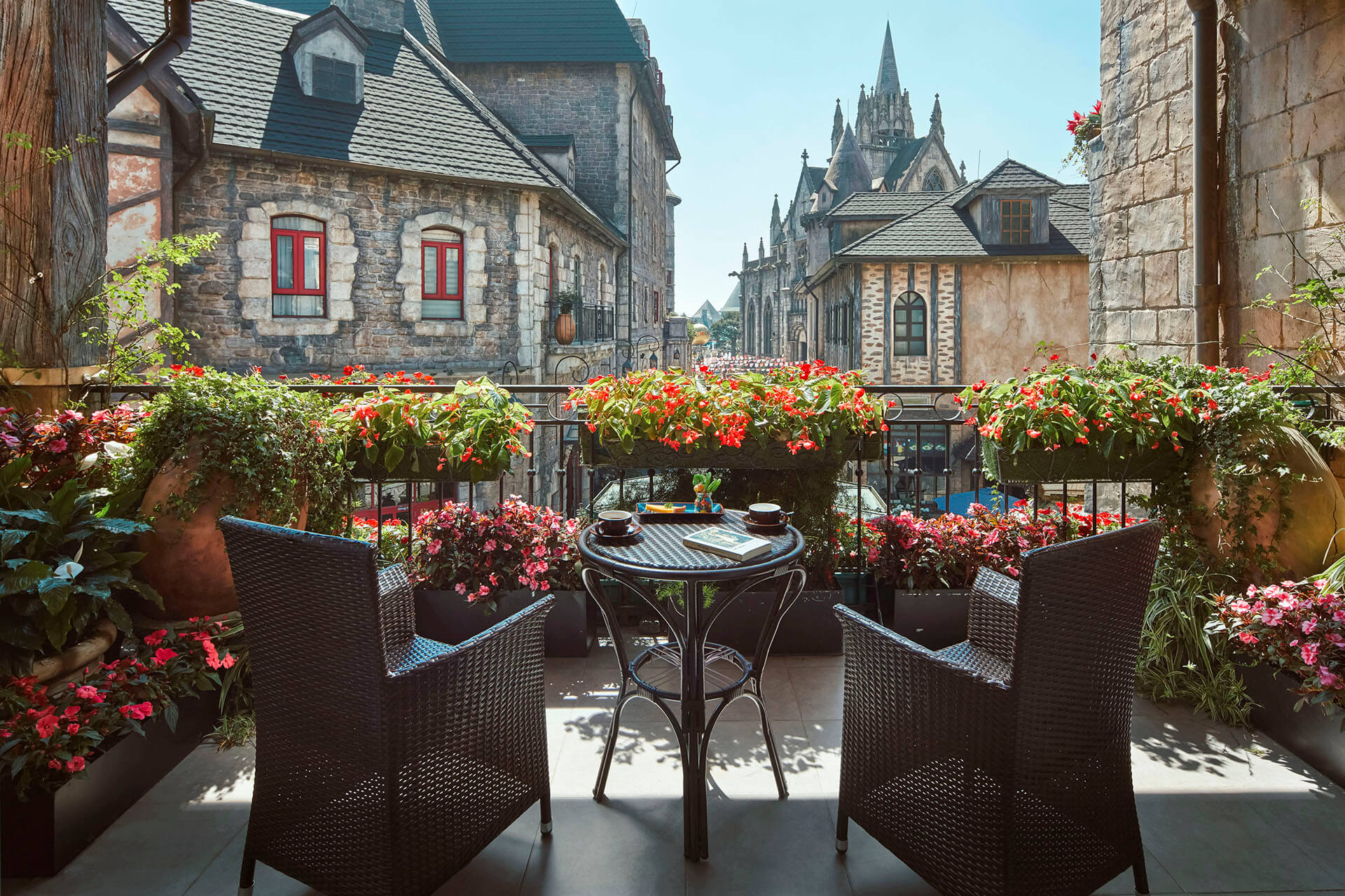 Café tables on a terrace in a European-style mountain village with people strolling