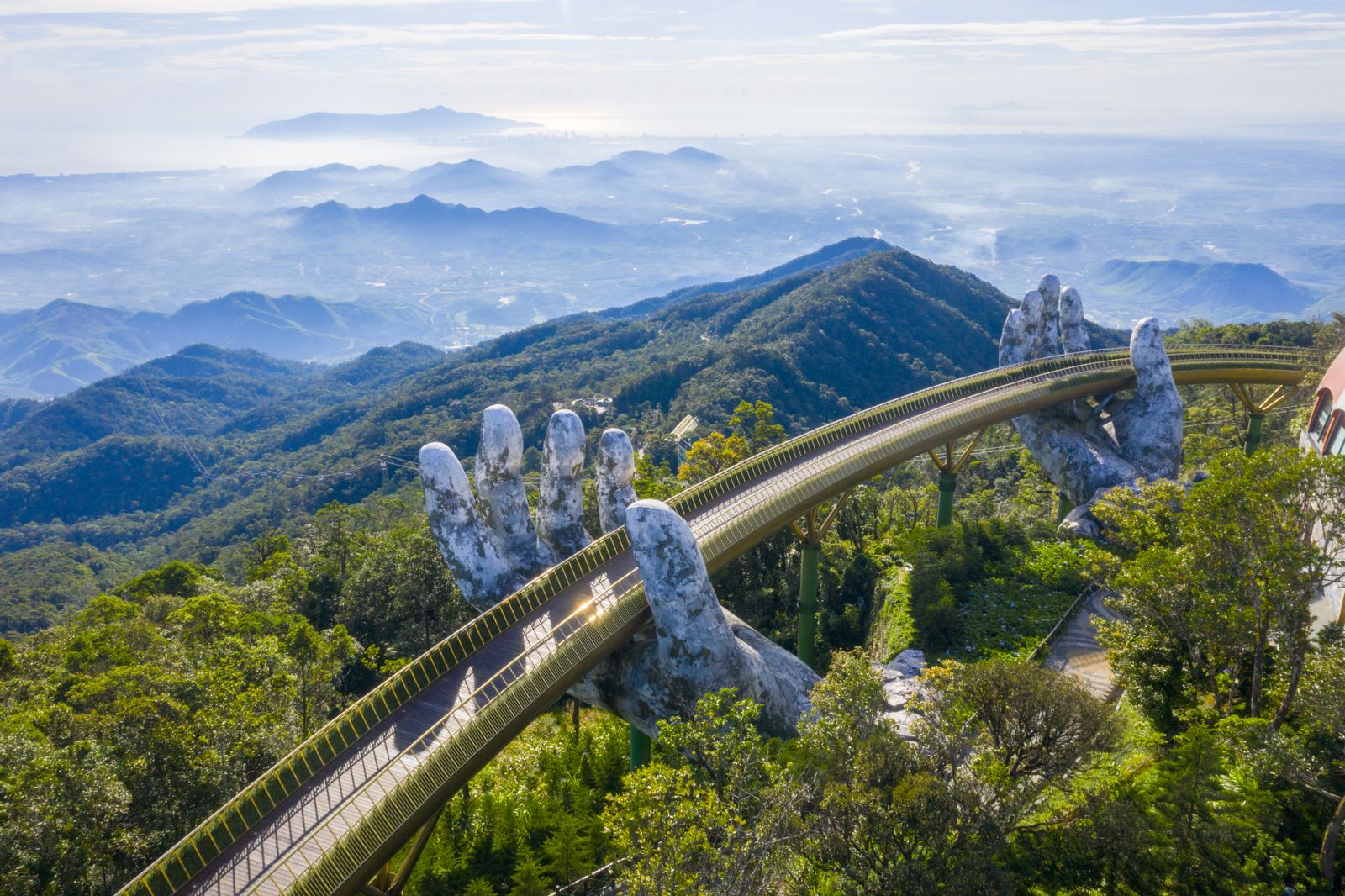 The Golden Bridge held up by two giant stone-look hands above the forest at Ba Na Hills