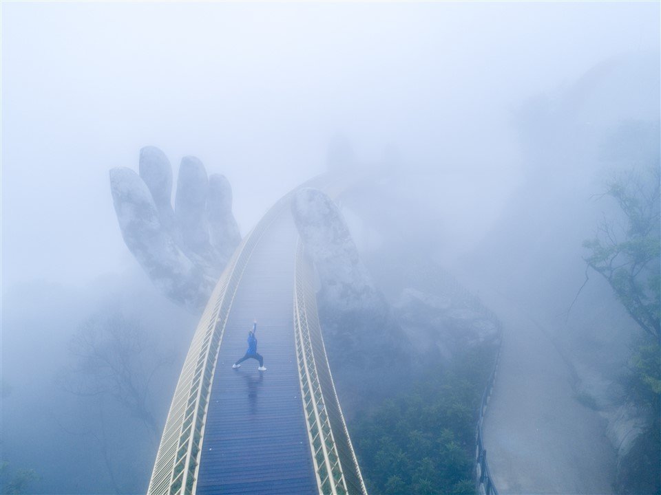 The curved golden walkway of the Golden Bridge disappearing into the clouds
