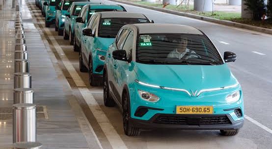 Green SM electric taxis lined up at an airport pickup lane in Vietnam