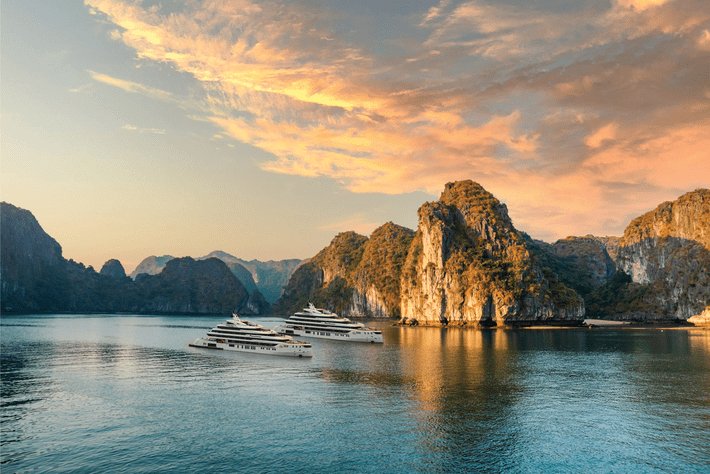 A cruise boat among the limestone islands of Ha Long Bay at sunrise