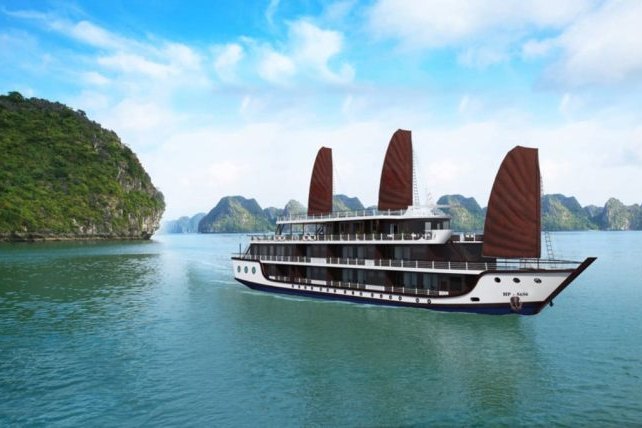 A cruise ship with traditional red-brown sails passing limestone islands in Ha Long Bay