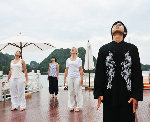 Guests doing tai chi on the deck of a cruise ship at sunrise in Ha Long Bay