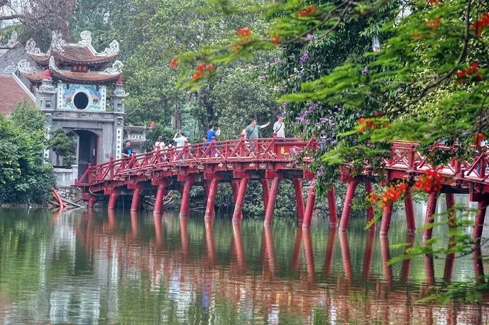 The red Huc Bridge over Hoan Kiem Lake in Hanoi, with visitors walking across it