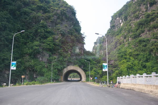 A road leading into a tunnel through limestone karst cliffs in Ninh Binh
