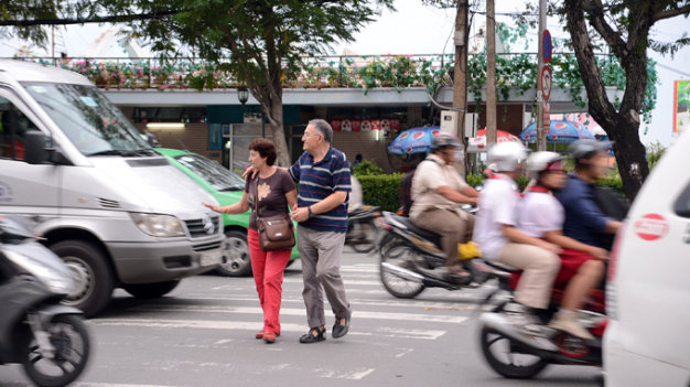 Pedestrians crossing a street full of motorbikes in Hanoi's Old Quarter