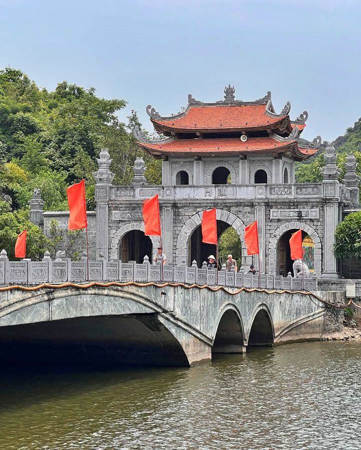 A stone gate and arched bridge hung with red flags at the Hoa Lu ancient capital in Ninh Binh