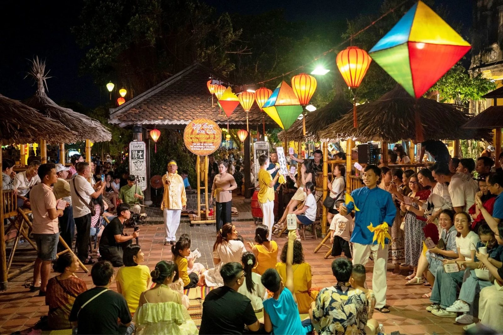 Bai choi performers in traditional dress singing to a crowd in Hoi An at night