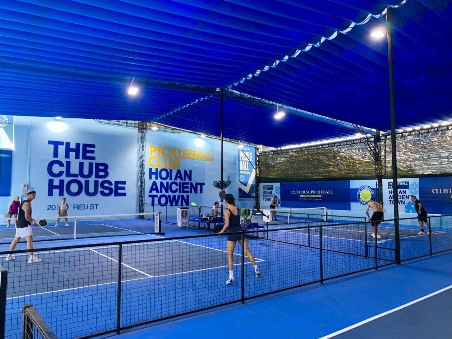 Players on the covered blue courts at The Club House pickleball club on Ba Trieu Street in Hoi An