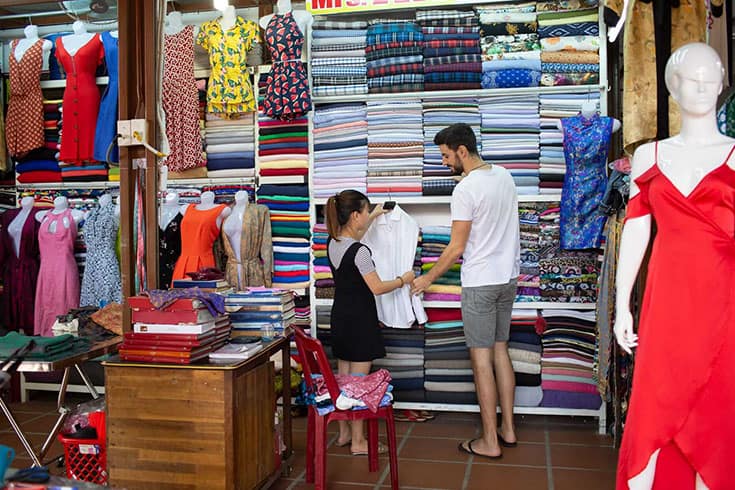 A tailor measuring a customer for a made-to-measure suit in a Hoi An shop