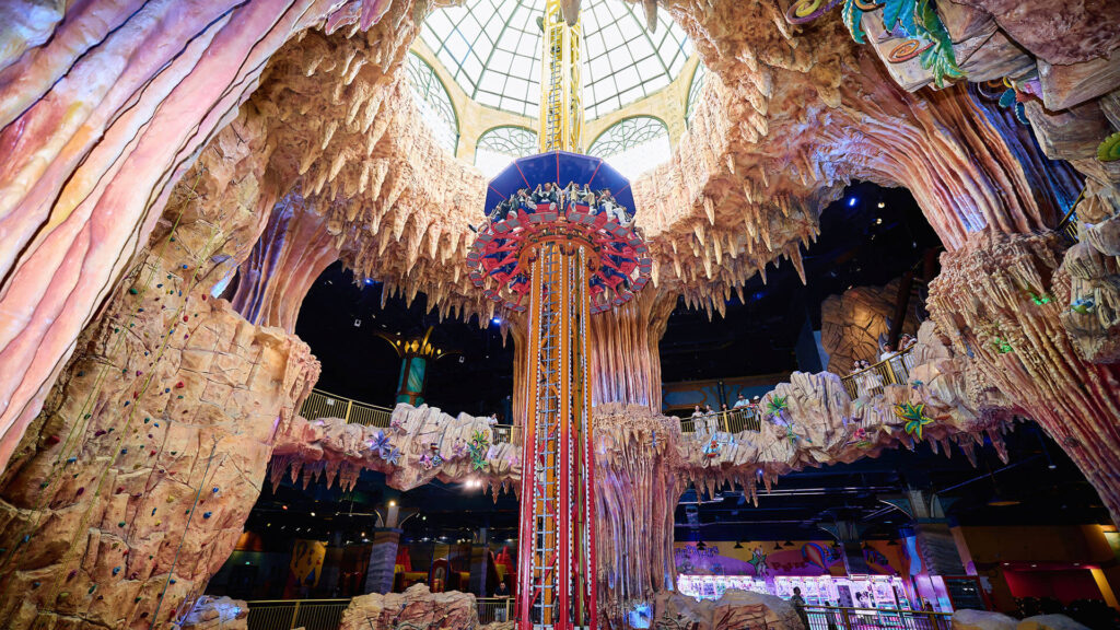 Brightly lit rides and games inside a large indoor amusement park