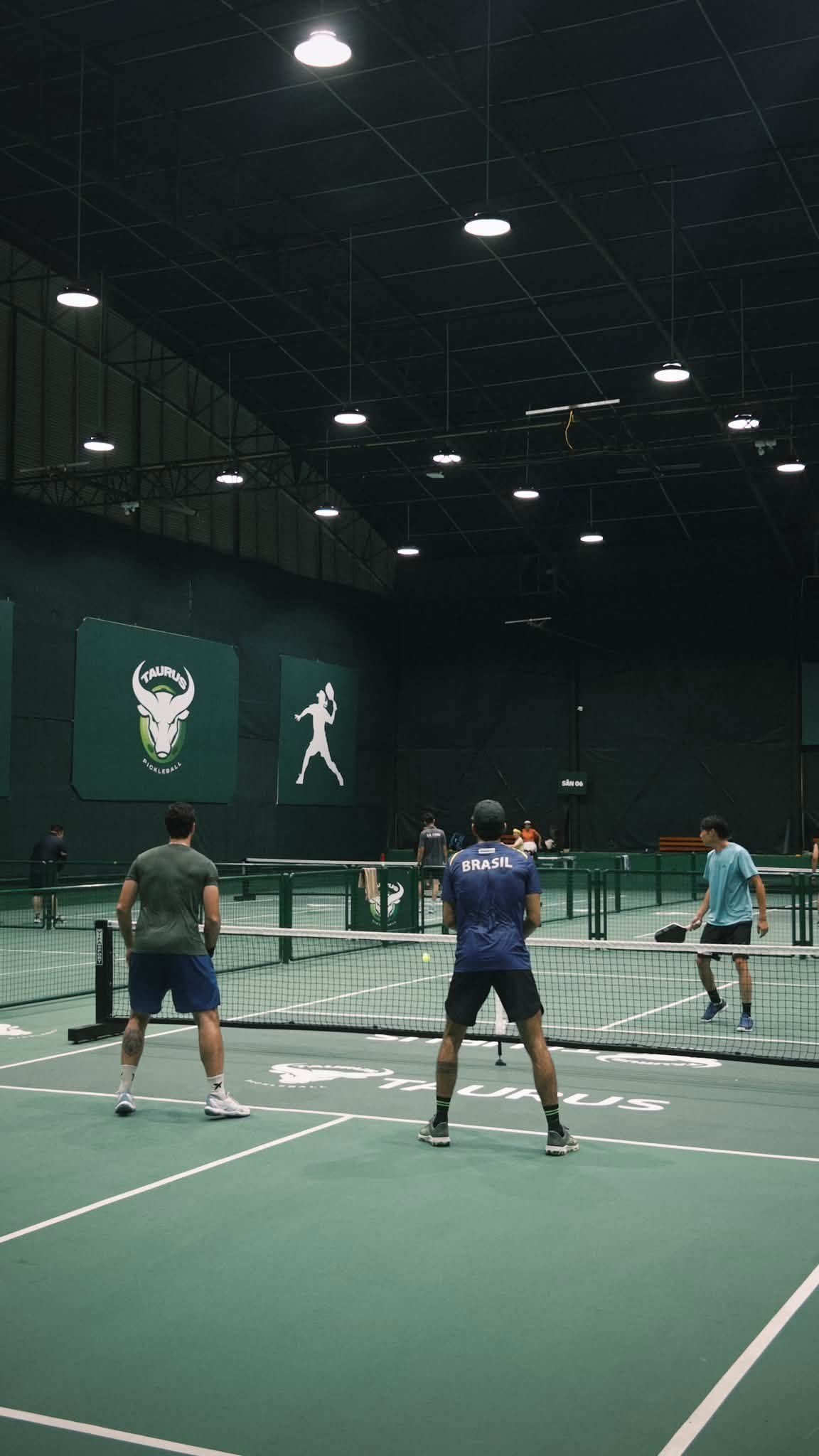 Doubles games on an indoor pickleball court in Vietnam in the evening