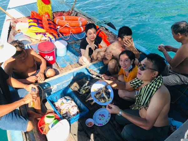 A group sharing freshly grilled fish aboard a fishing boat in the Nam Du Islands