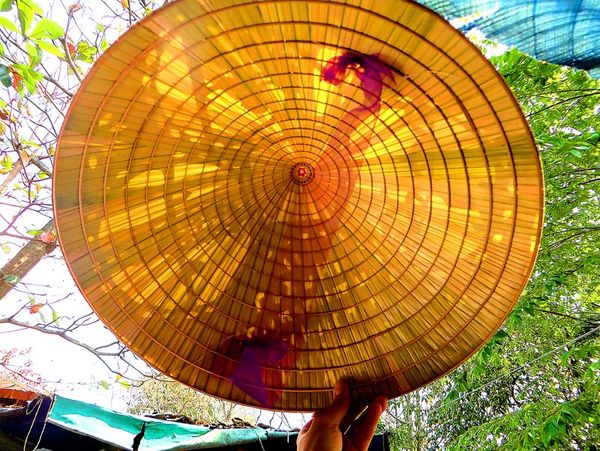 A Hue poem conical hat held up to the light, showing the hidden pictures inside