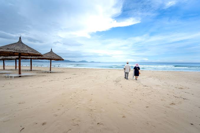 An older couple walking along a quiet beach in Vietnam
