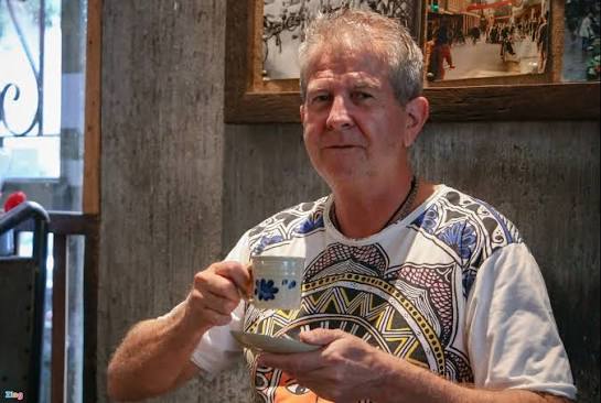 An older foreign man sitting alone at a café table in Vietnam