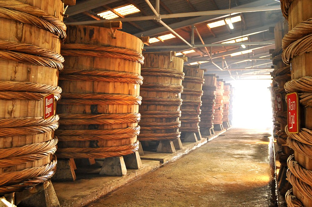Large wooden barrels of fermenting fish sauce at a traditional factory in Phu Quoc