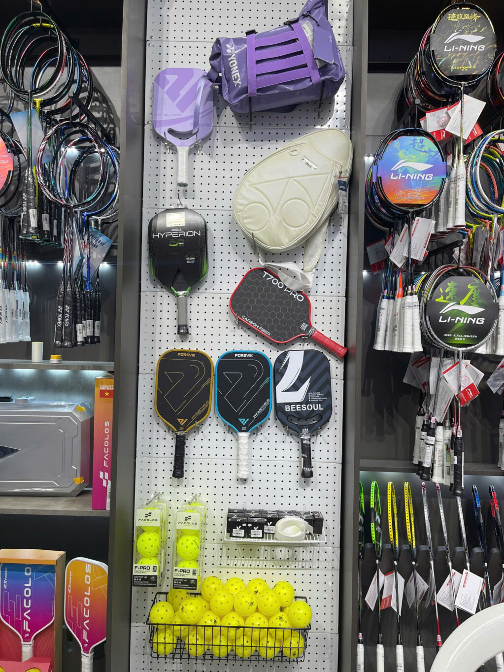 Paddles, bags and a basket of pickleball balls on a racket shop wall in Vietnam