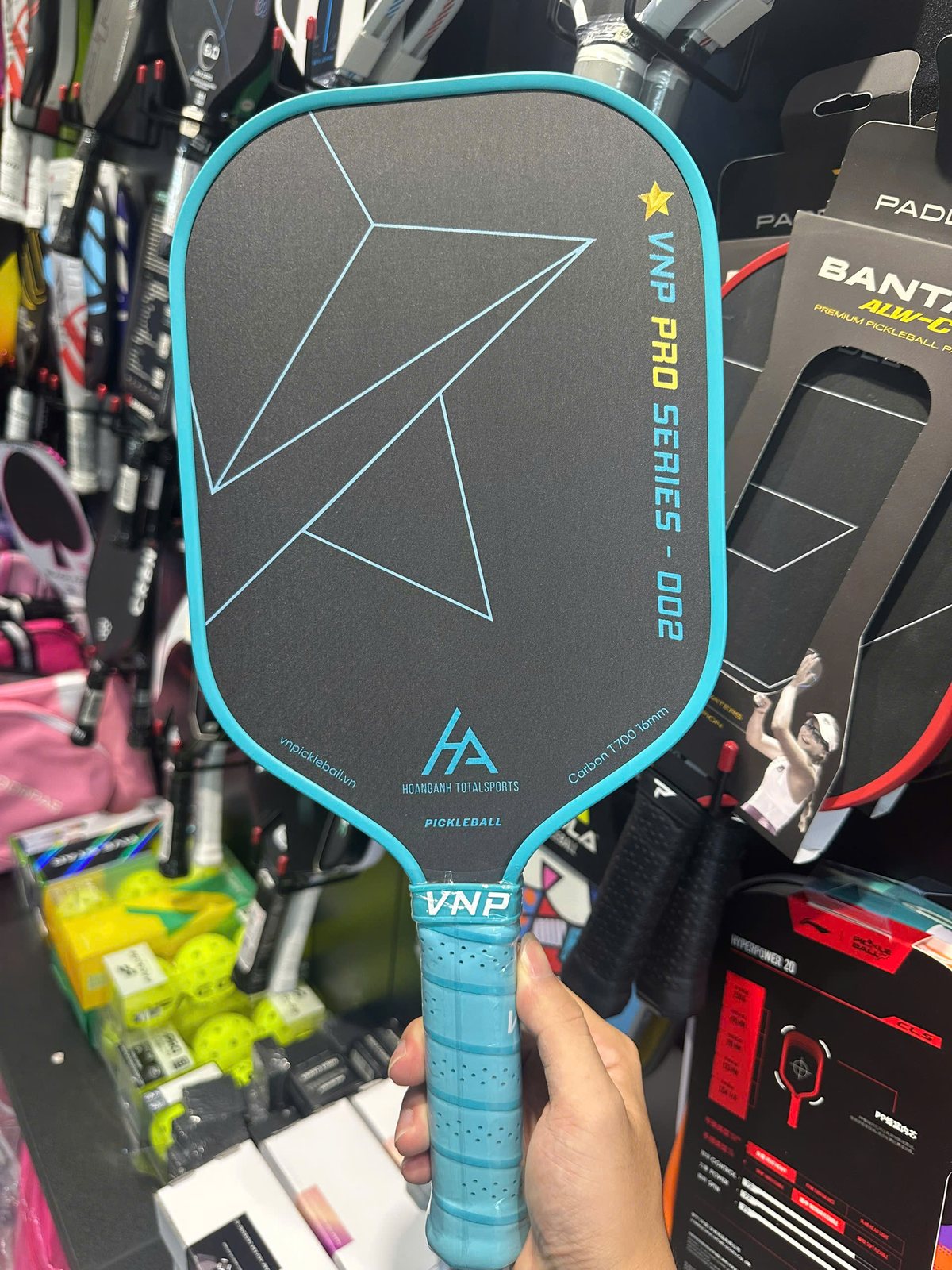 A visitor holding a pickleball paddle to test the grip in a sports shop in Vietnam