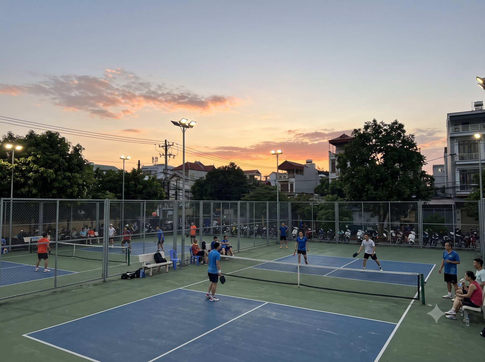 A pickleball court in Vietnam at sunset with players finishing a game
