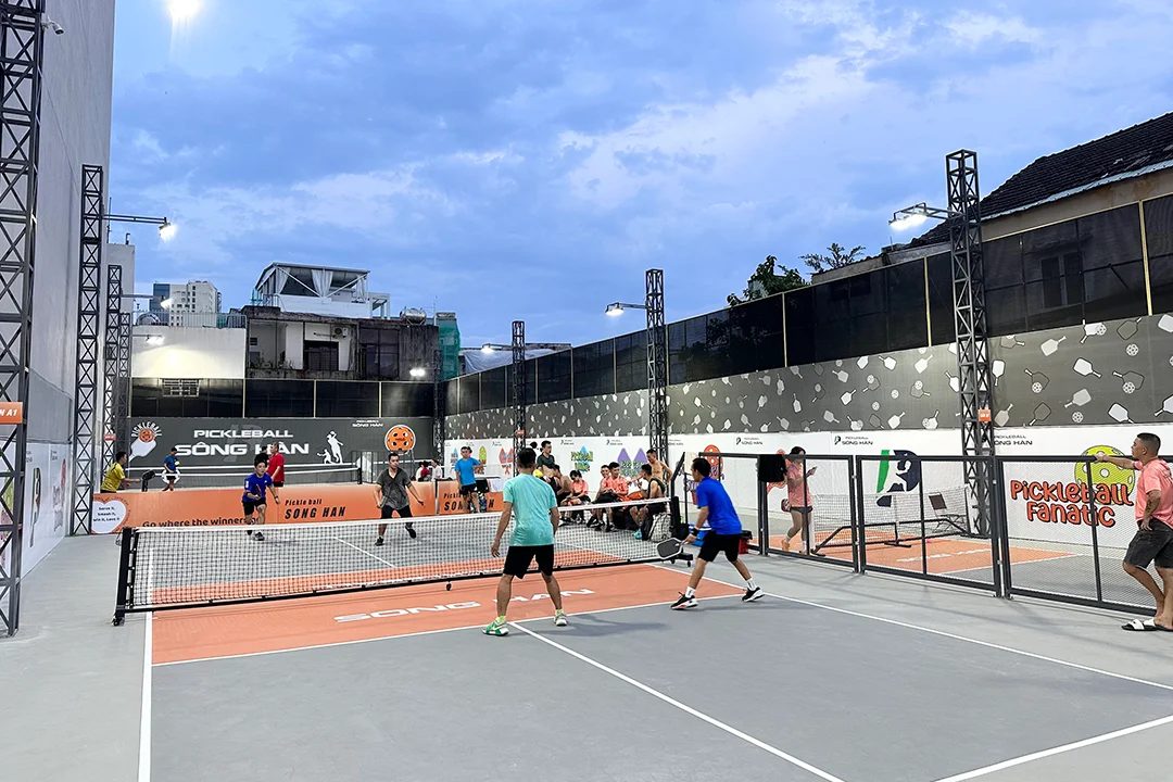 Players in an evening doubles game at a floodlit pickleball court in Da Nang, Vietnam