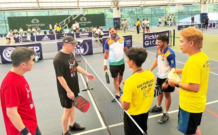 Visitors and local players smiling together after a pickleball game in Vietnam