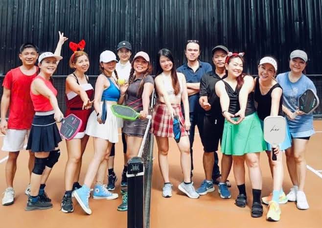 A group of local and visiting players posing for a photo after a pickleball session in Vietnam