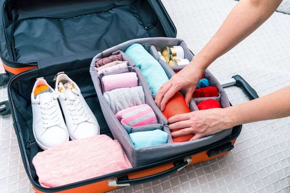 A suitcase packed for a pickleball trip to Vietnam with paddle, shoes, shirts and sunscreen