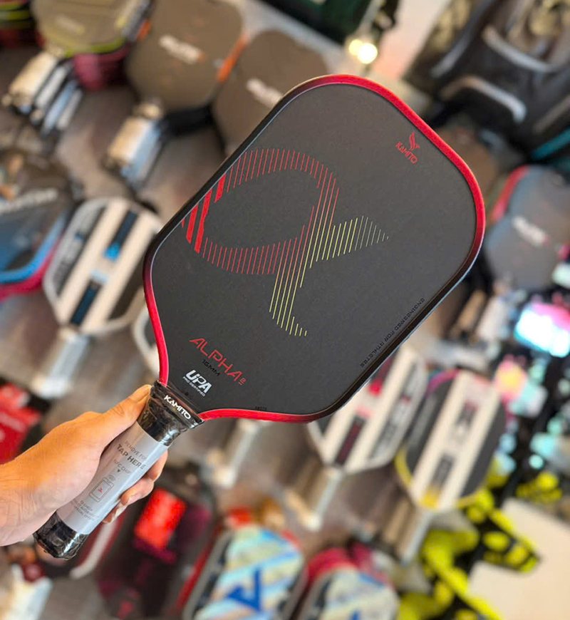 Close-up of a pickleball paddle in a shop, with the approval mark printed near the handle