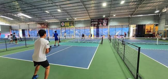 Two pickleball paddles and yellow balls lying on a blue court