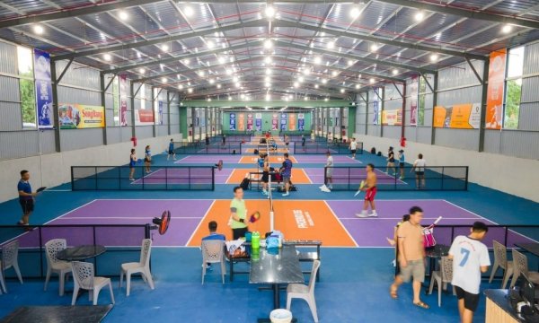 Players resting at tables under the roof of a covered pickleball club in Vietnam