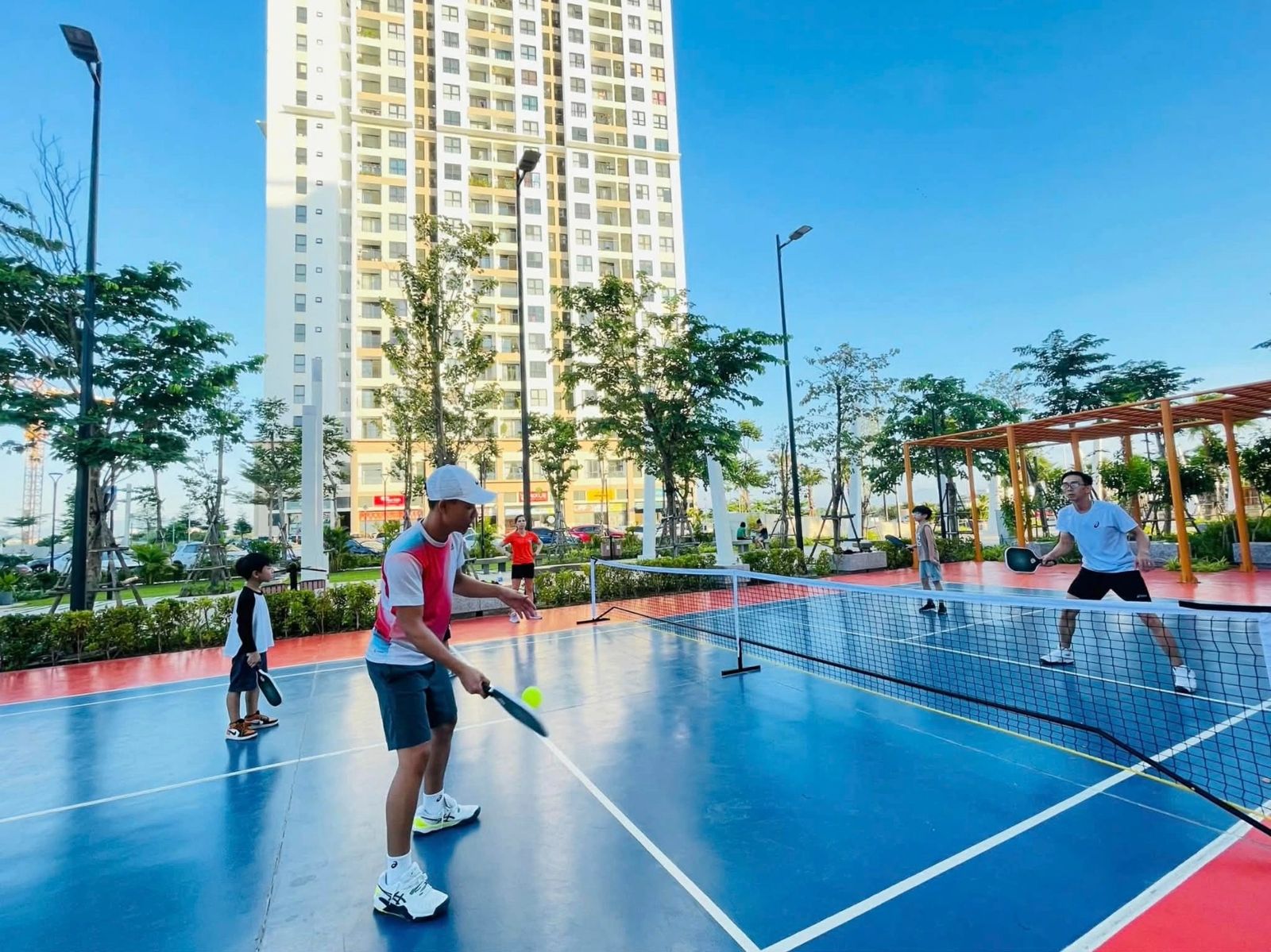 Two players in light, breathable kit on a pickleball court at sunrise in Vietnam