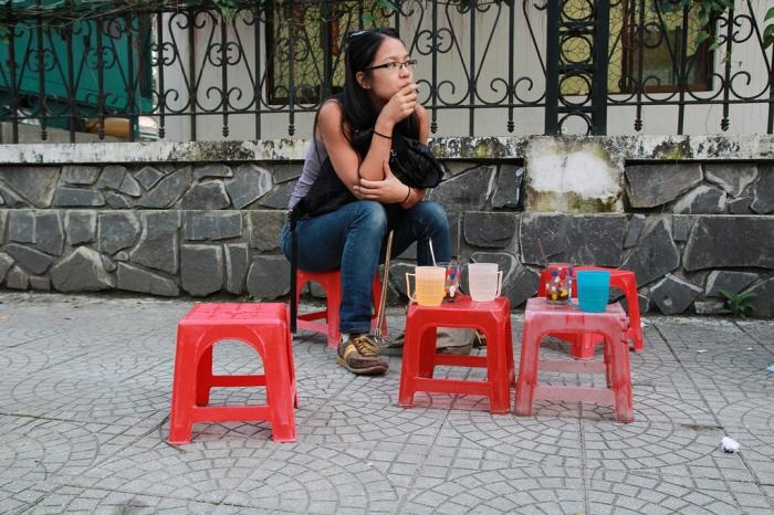 Locals drinking coffee on small plastic stools in a Saigon alley