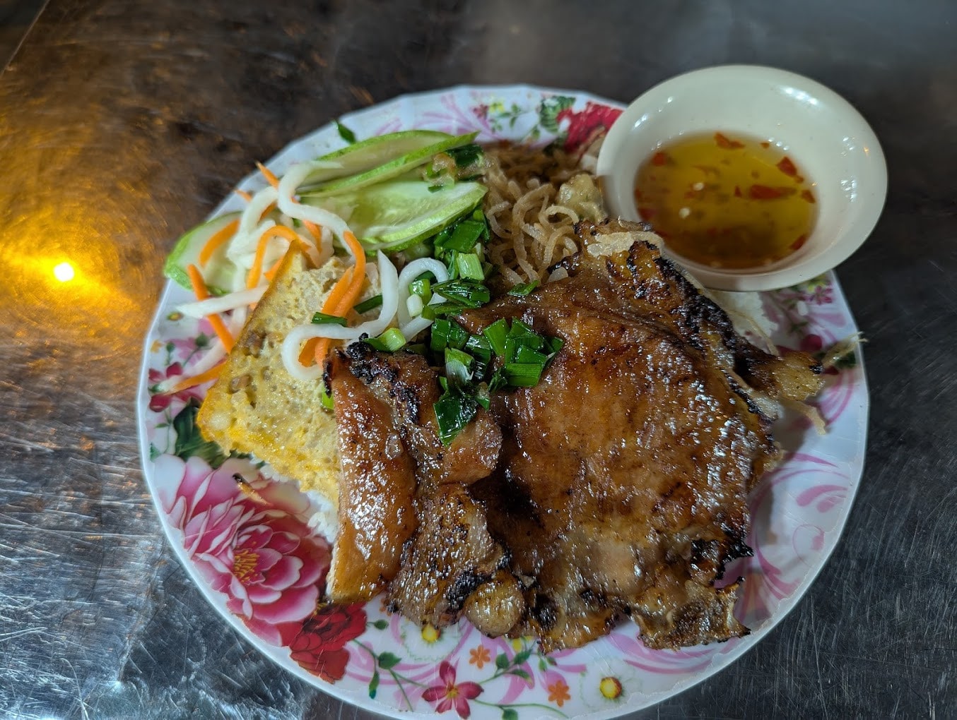A plate of com tam, broken rice with grilled pork chop, a Saigon street food classic