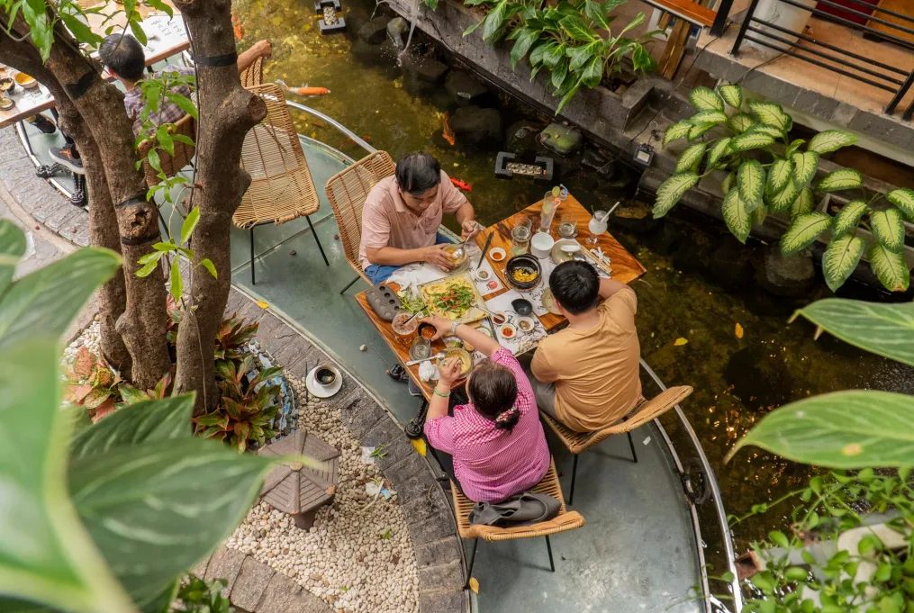 A family eating at a garden vegetarian restaurant with a koi pond in central Ho Chi Minh City