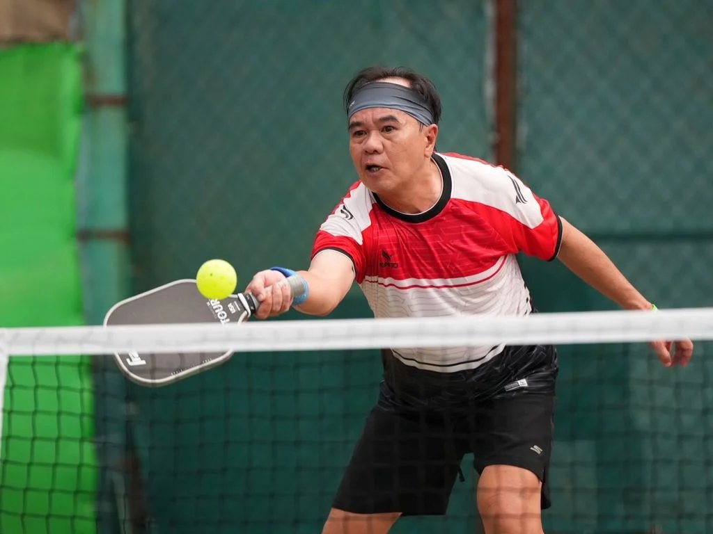 Older pickleball players enjoying a doubles game on a covered court in Vietnam