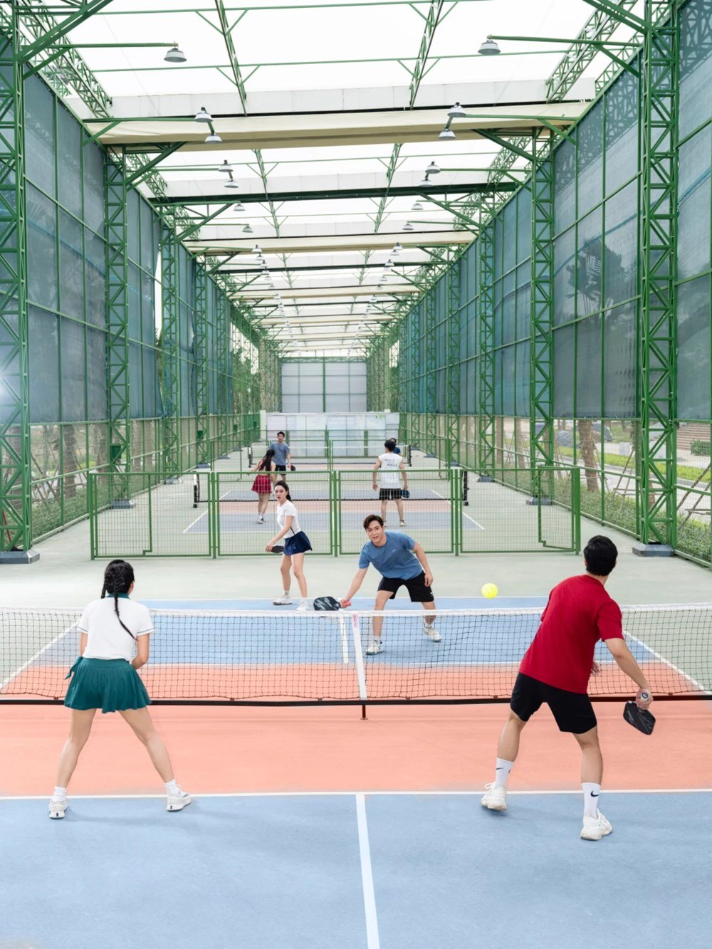 Players on covered pickleball courts under a steel roof at Sun Sports City in Phu Ly, Ninh Binh province