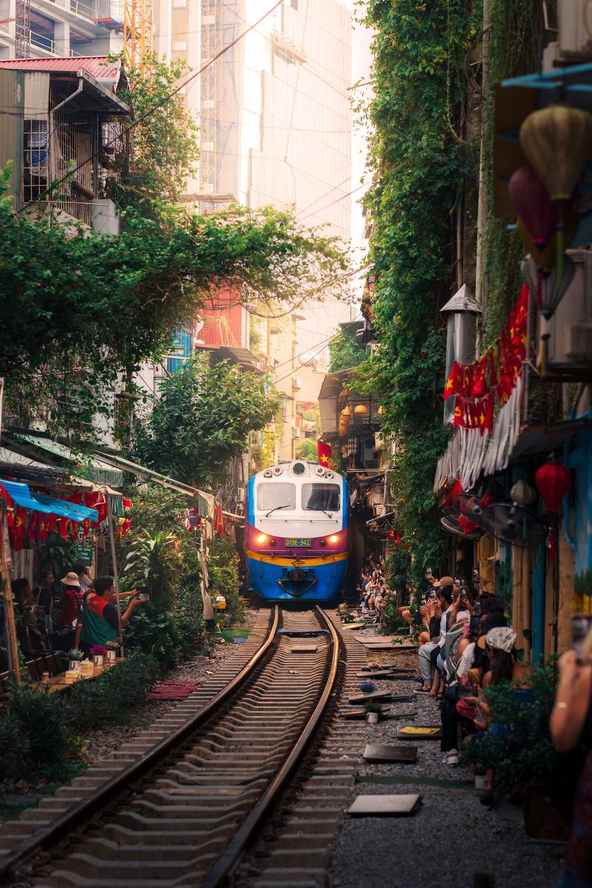 A train passing through the narrow Hanoi Train Street lined with cafes and onlookers