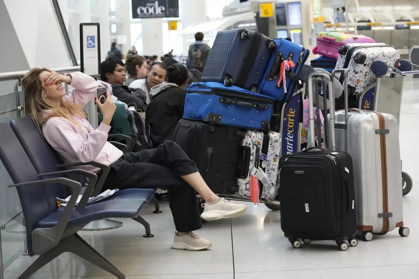 Tired travellers sitting with their luggage at an airport departure gate