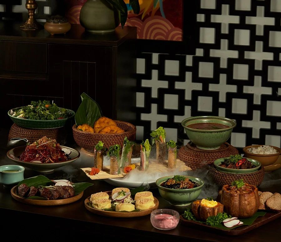A table of Vietnamese vegetarian dishes with tofu, mushrooms, fresh spring rolls and herbs