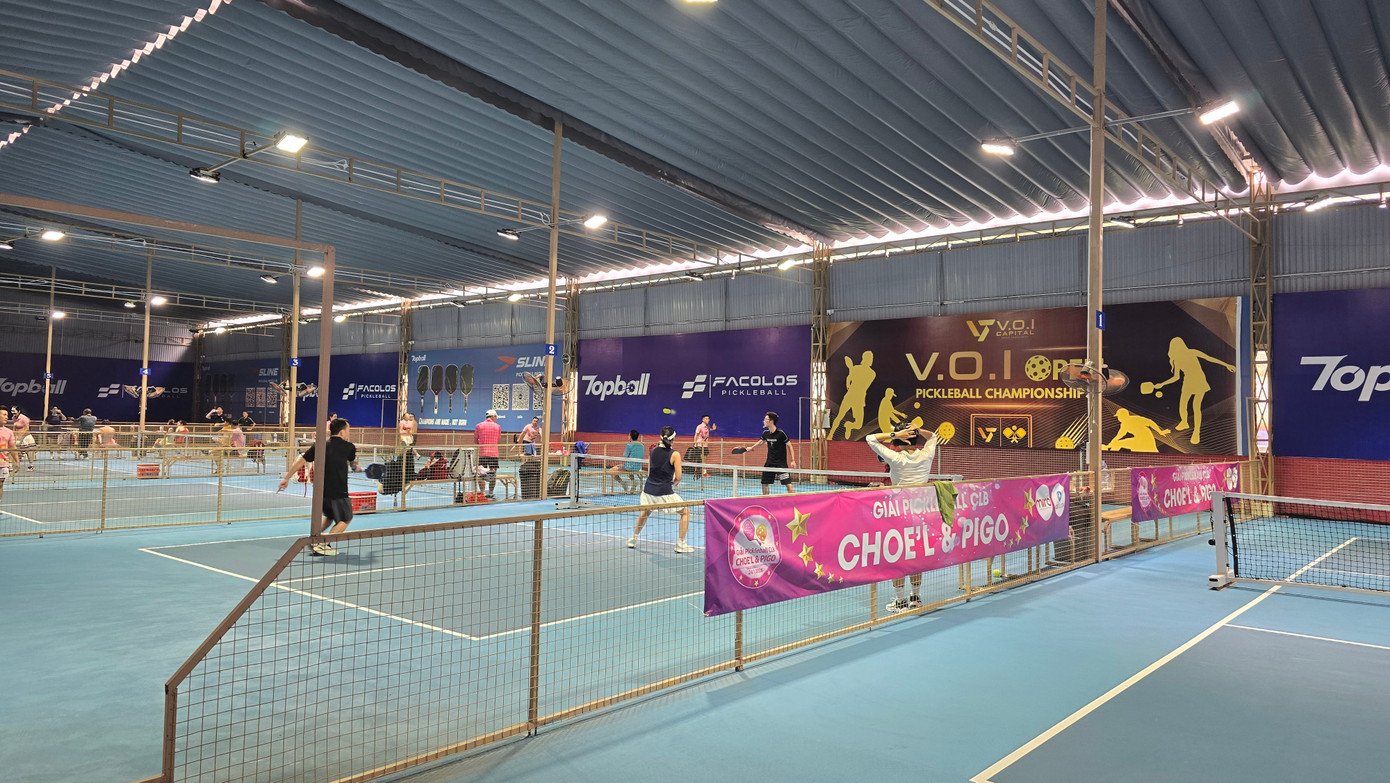 Players on a busy pickleball court in Vietnam in the early evening after work