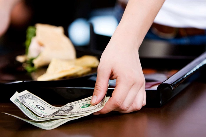 Vietnamese dong notes tucked under a plate on a restaurant table