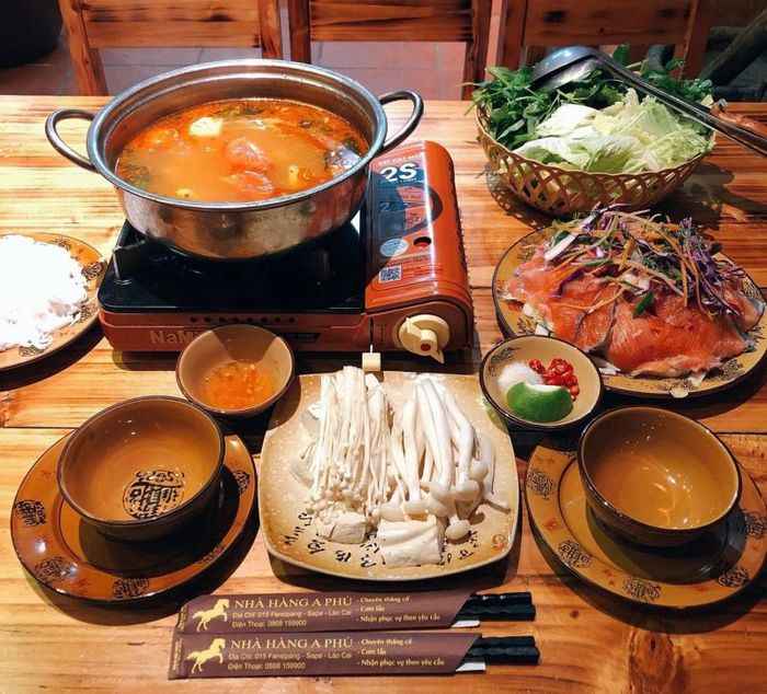 A bubbling hotpot and a tabletop grill with meat and vegetables on a restaurant table