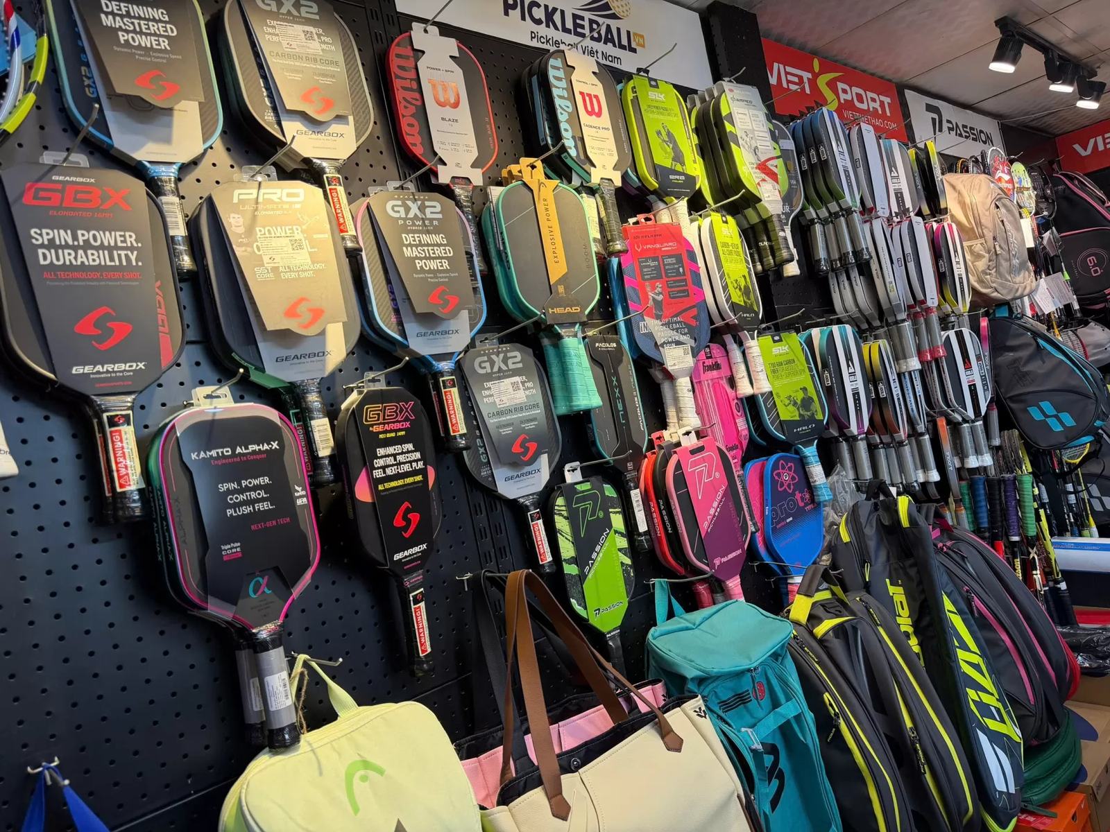 Paddles from Kamito and other brands on the wall of a racket shop in Vietnam